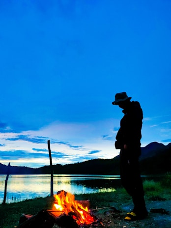Evening photo of Lara Croft silhouette against a campfire in the wilderness.