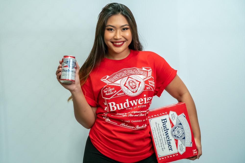 a woman in a red budweiser shirt holding a can of budweiser