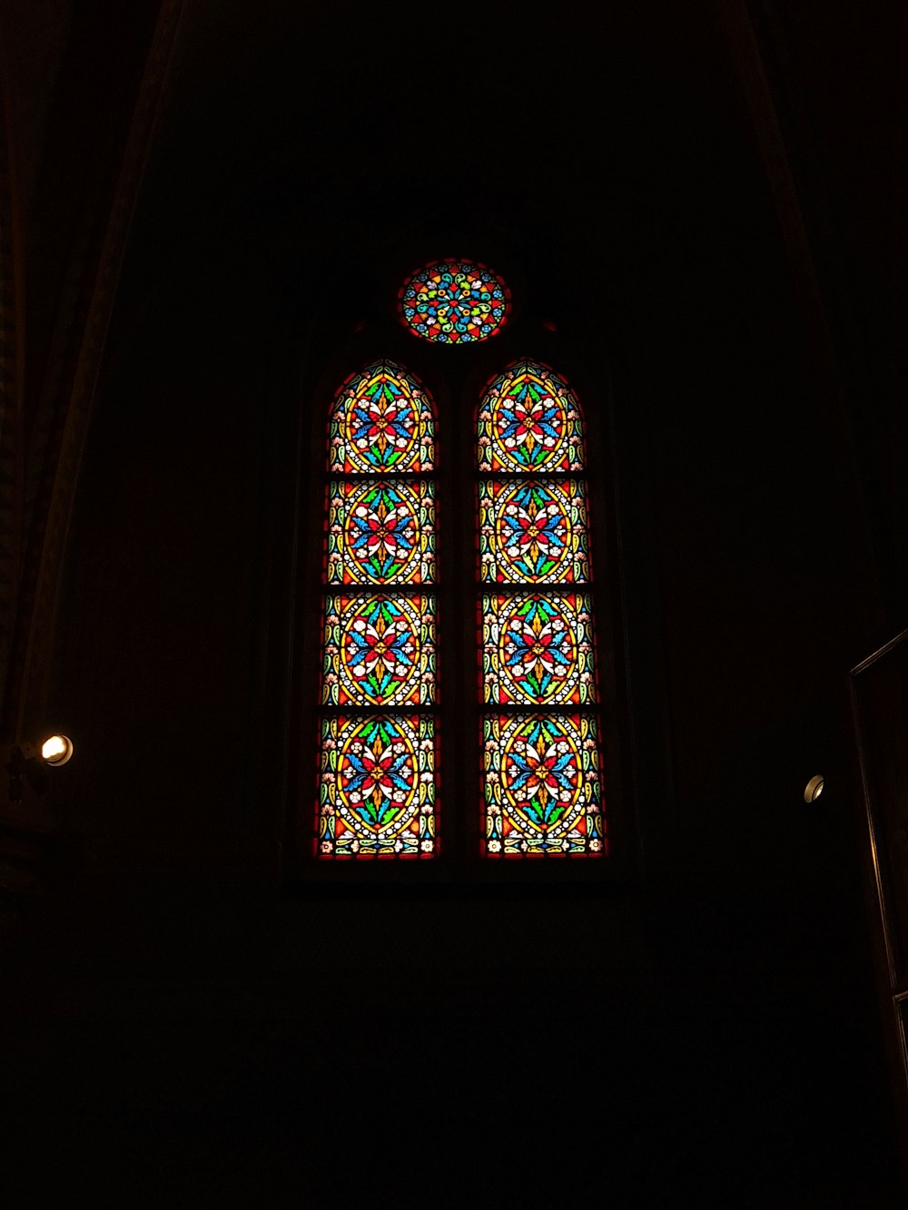 a large stained glass window in a dark room