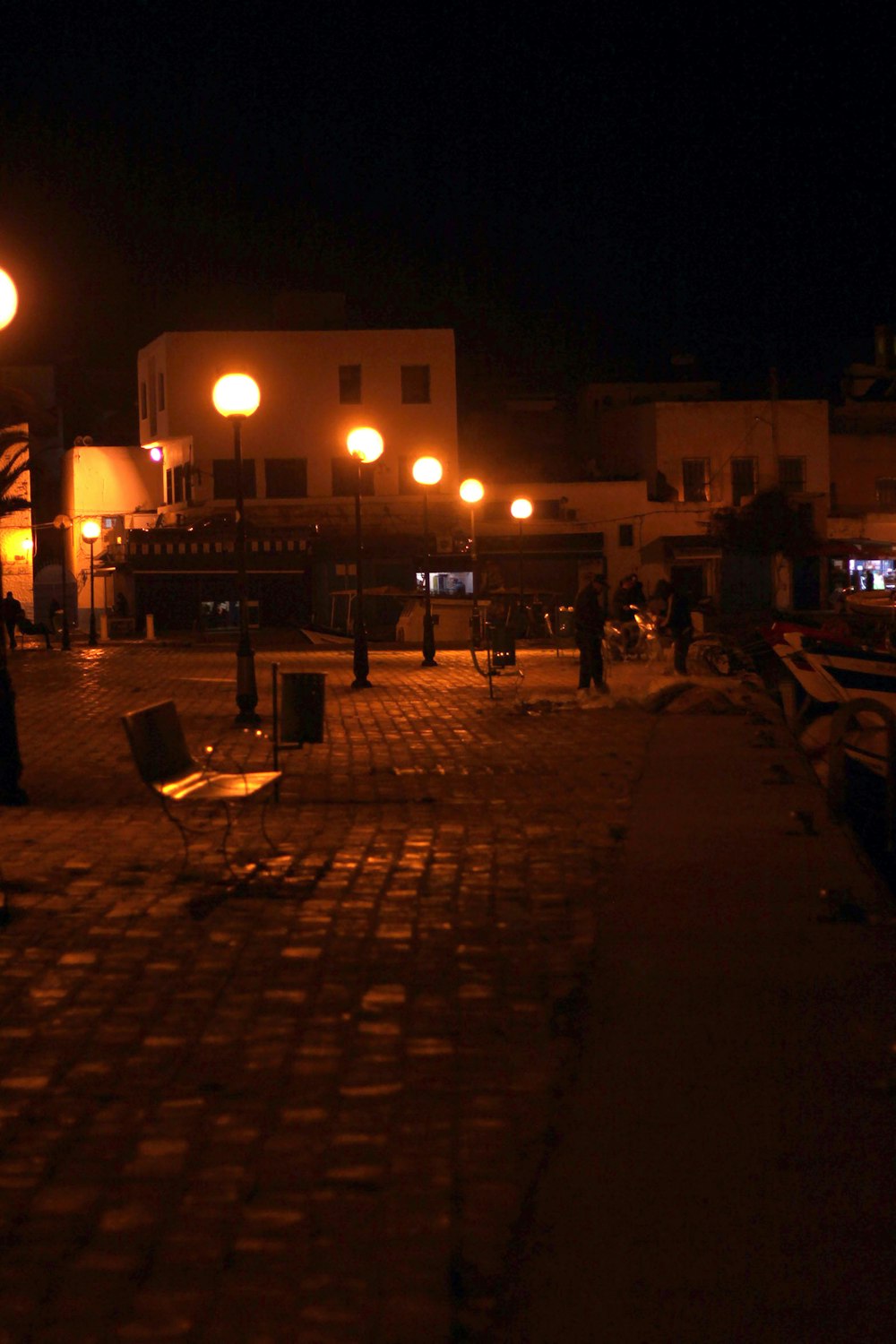 a street at night with people walking on the sidewalk