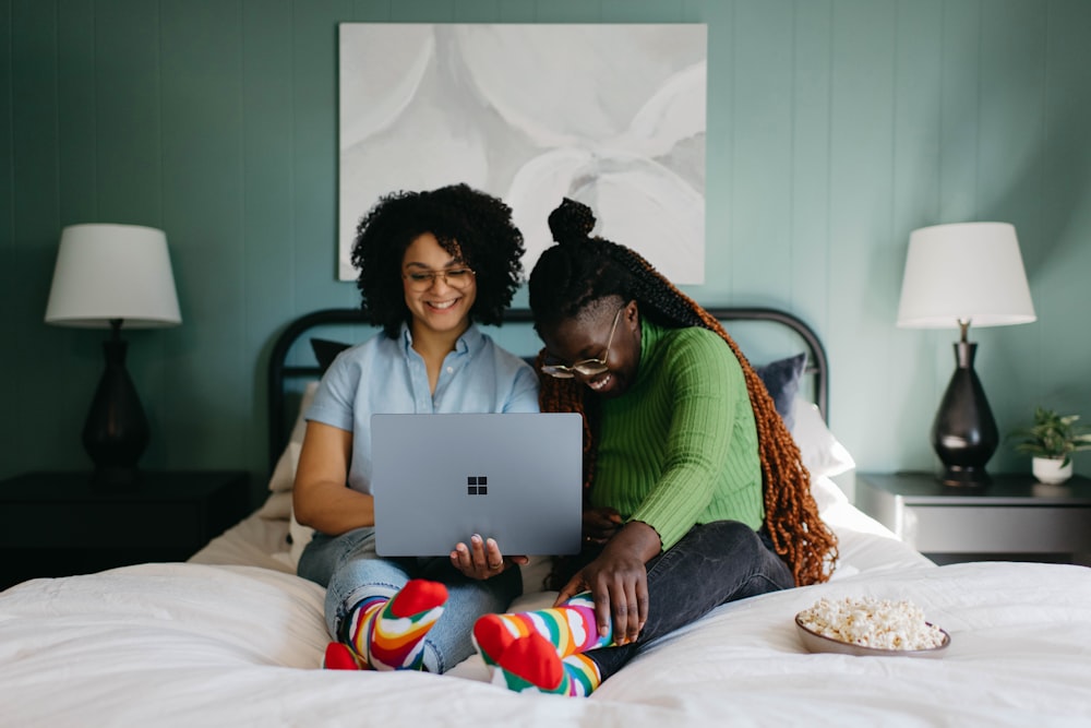 a woman sitting on a bed using a laptop