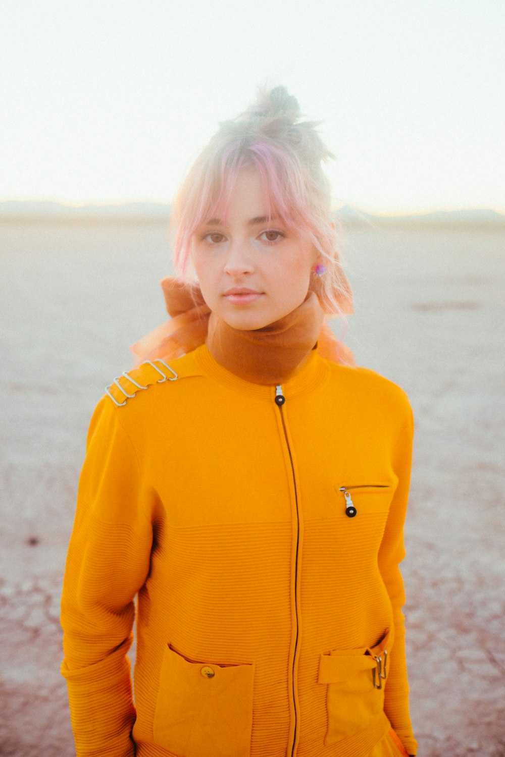 a woman with pink hair wearing a yellow jacket