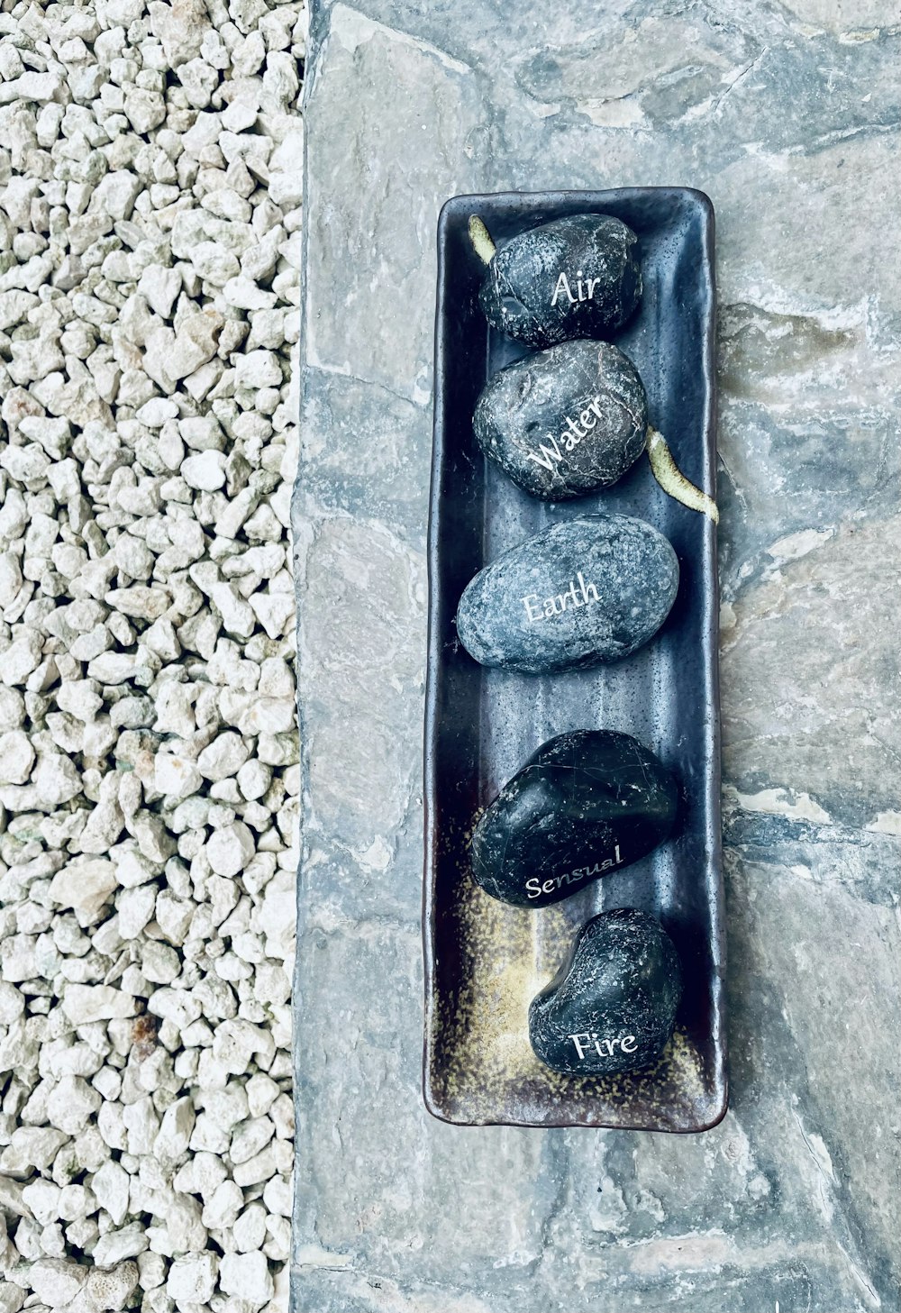 three rocks in a black tray on a stone floor