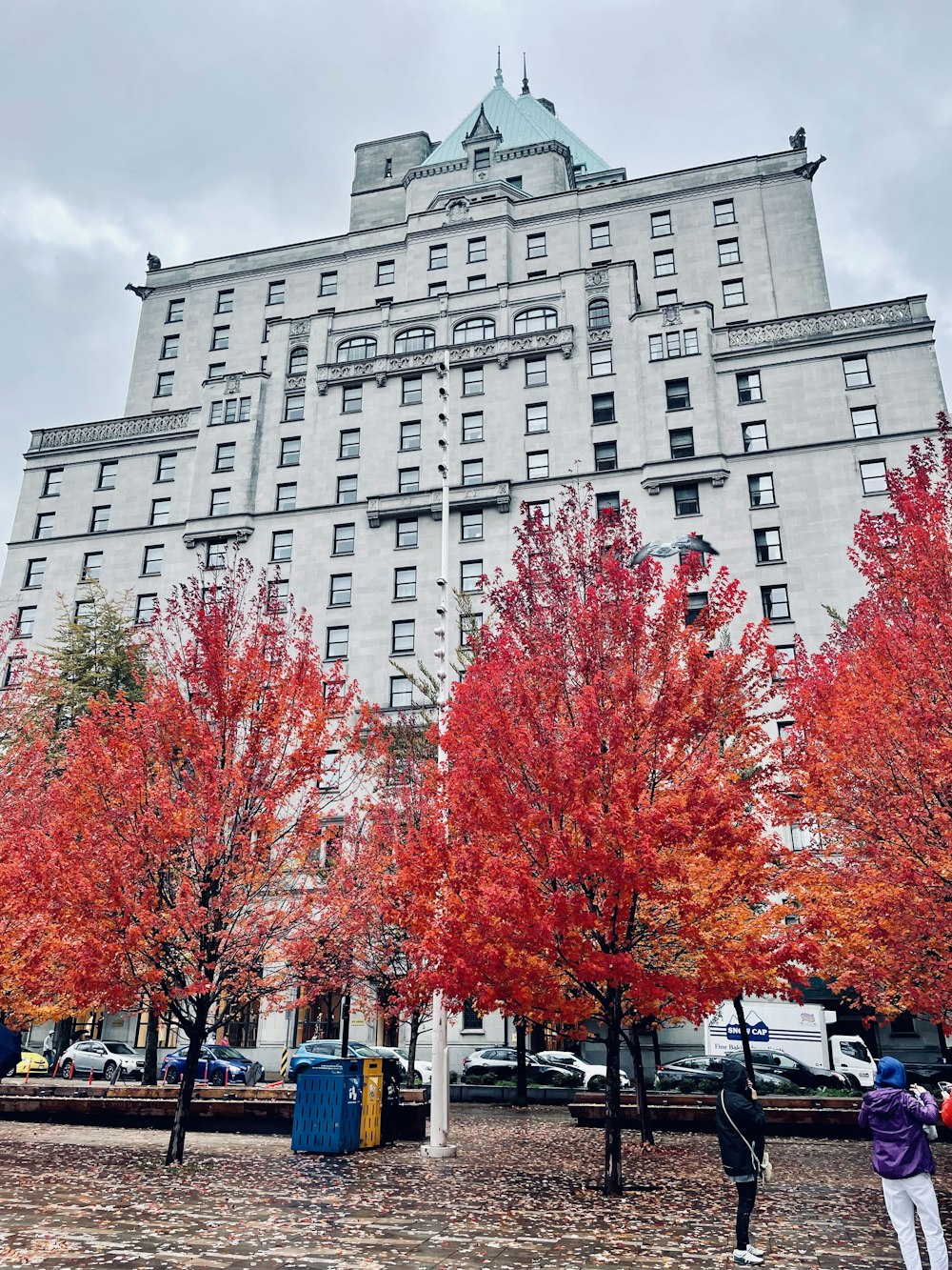 a tall building with a lot of red trees in front of it