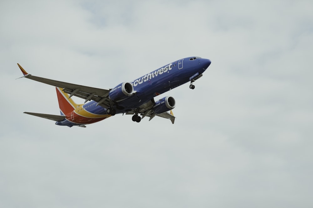 a blue and red airplane flying in the sky