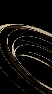 Black and metallic rings stacked on a matte black leather surface highlighting texture contrasts.