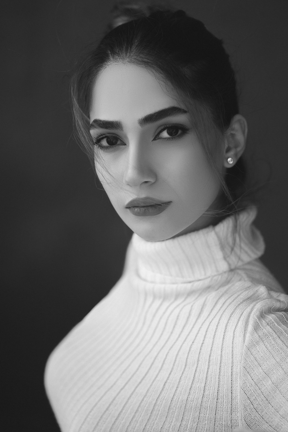 a black and white photo of a woman wearing a turtle neck sweater