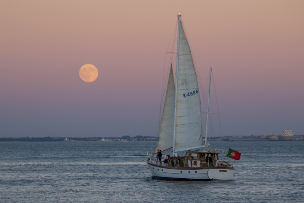 a sailboat with a full moon in the background