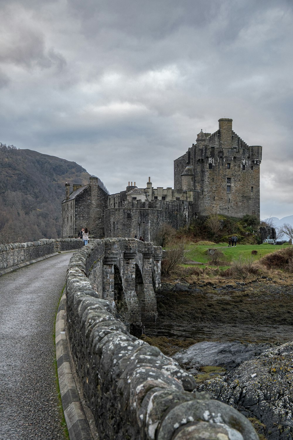 Un puente de piedra que conduce a un castillo en un día nublado