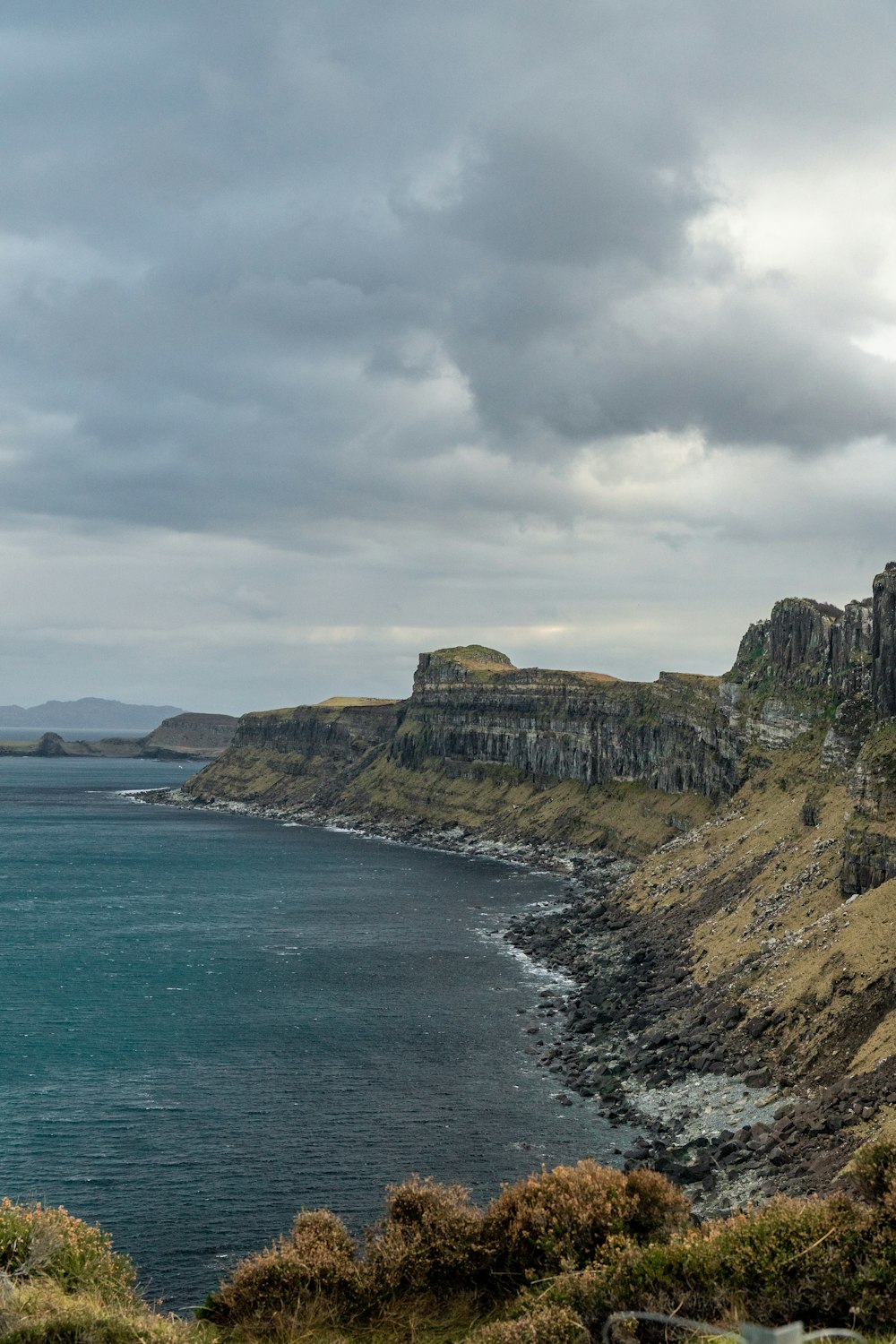 a large body of water sitting next to a lush green hillside