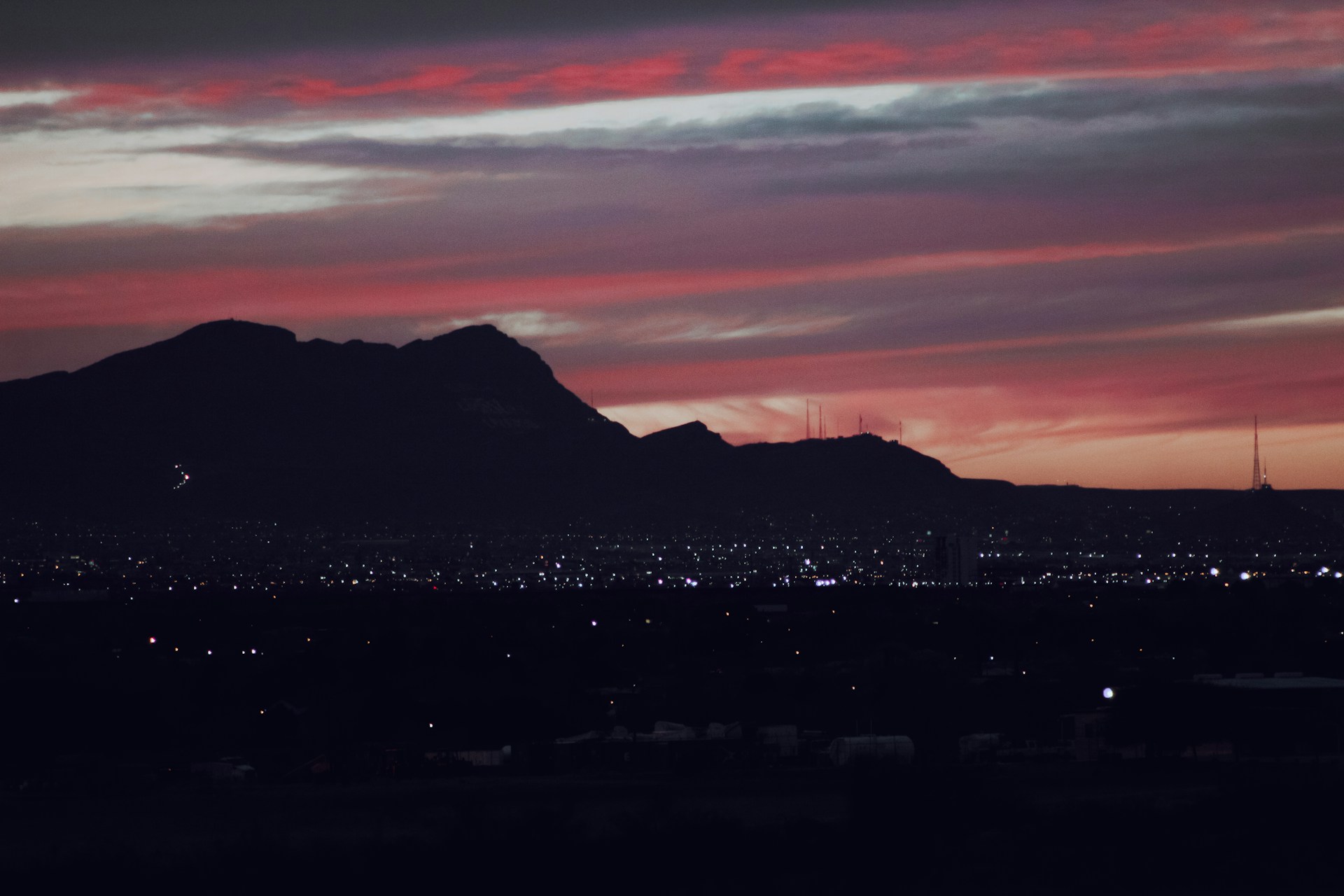 a sunset view of a city with a mountain in the background