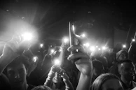 Black and white photo of youth faces illuminated by phone screens, absorbed in storytelling.