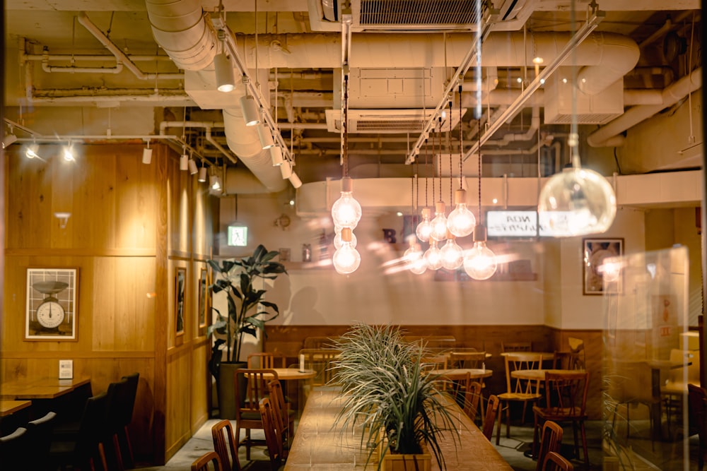 a restaurant with wooden tables and chairs and hanging lights