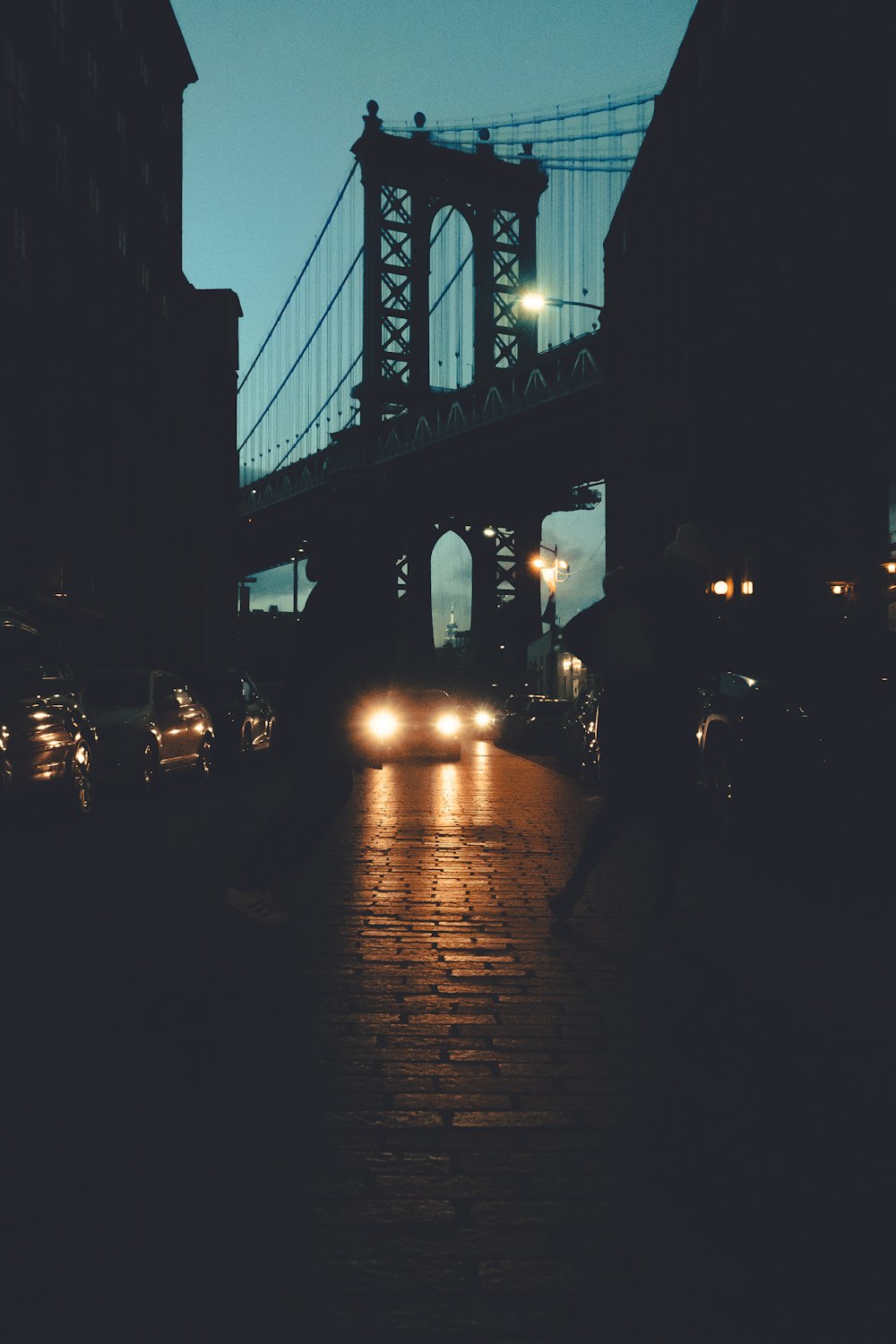 a city street at night with a bridge in the background
