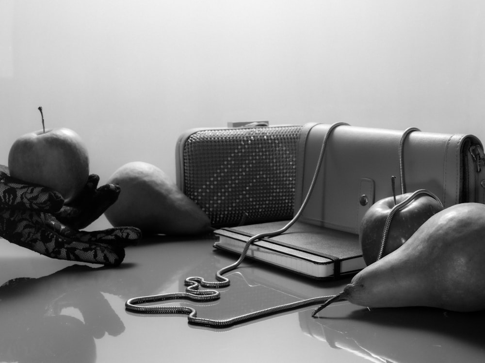 a black and white photo of a purse and apples