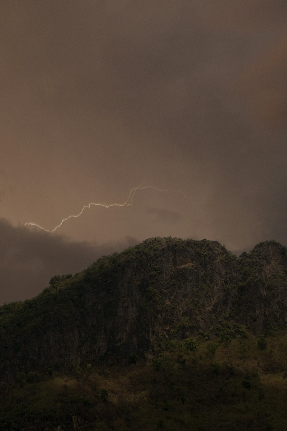 a large mountain with a lightning bolt in the sky