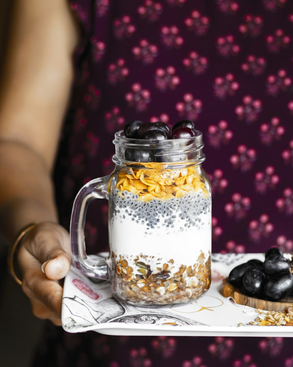 a person holding a tray with a jar of food on it