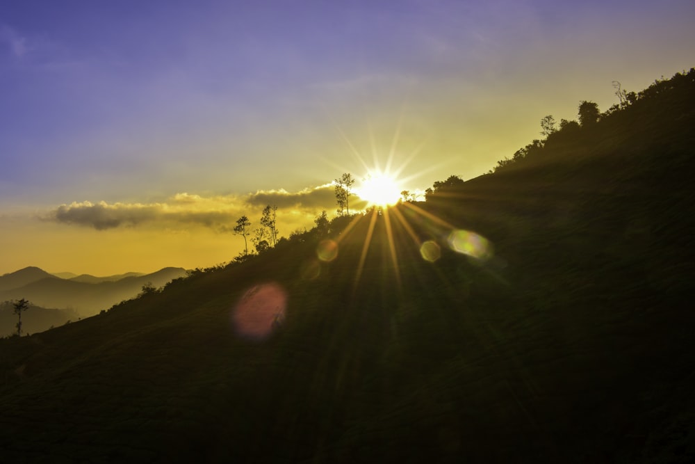 the sun is setting on a mountain side