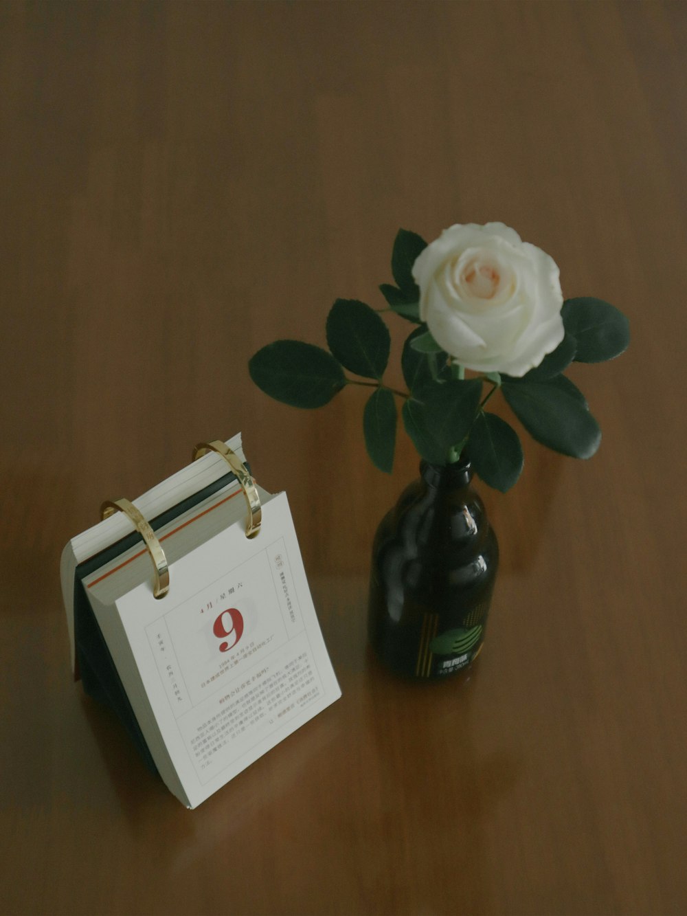 a white rose in a vase next to a calendar