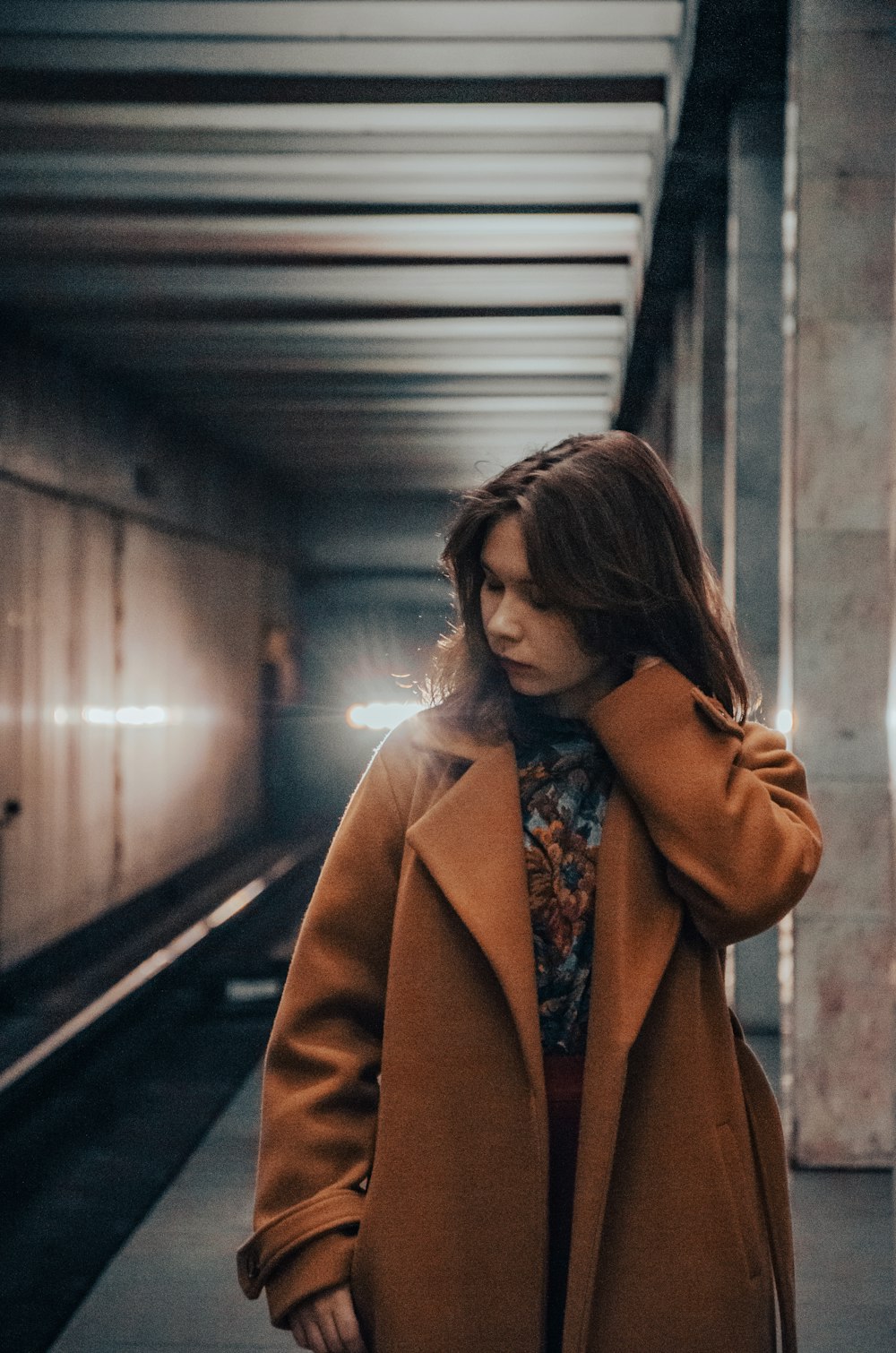 a woman standing in a subway station with her hand on her head