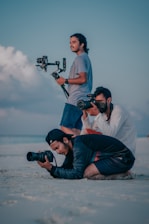 a couple of men sitting on top of a sandy beach