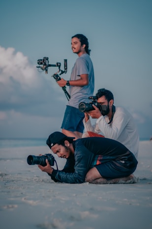 a couple of men sitting on top of a sandy beach