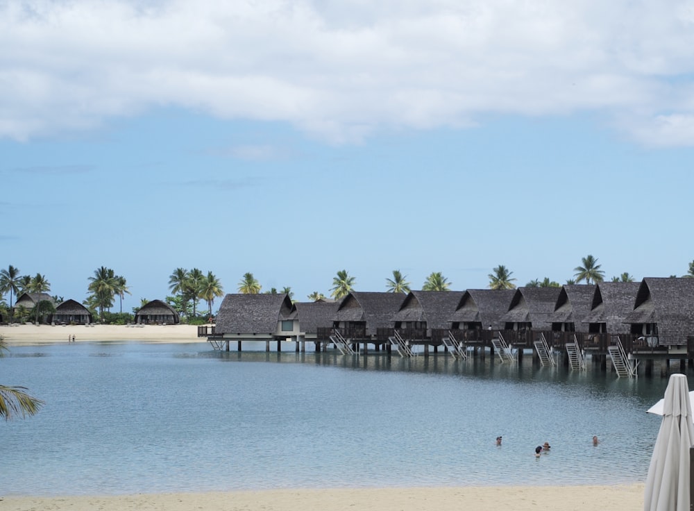 a row of huts sitting on top of a beach next to a body of water