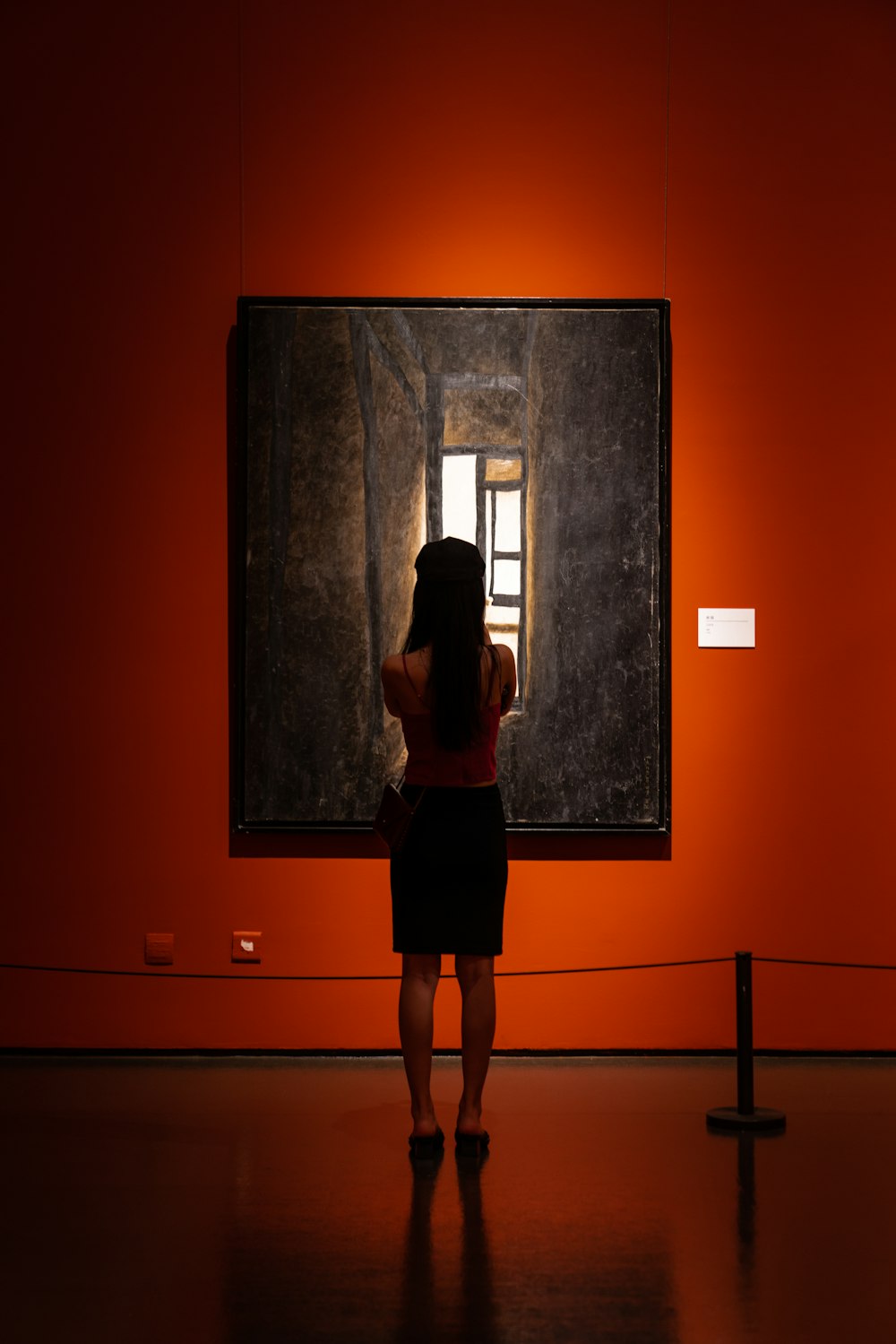 a woman standing in front of a painting in an orange room