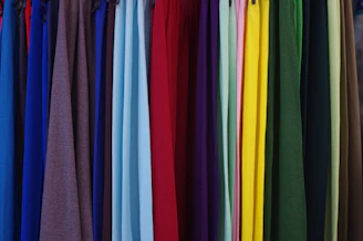 a bunch of different colored shirts hanging on a rack