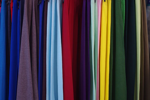 a bunch of different colored shirts hanging on a rack