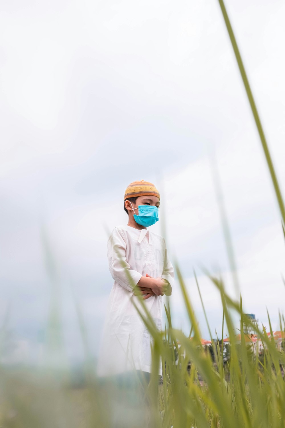 a man standing in a field wearing a face mask
