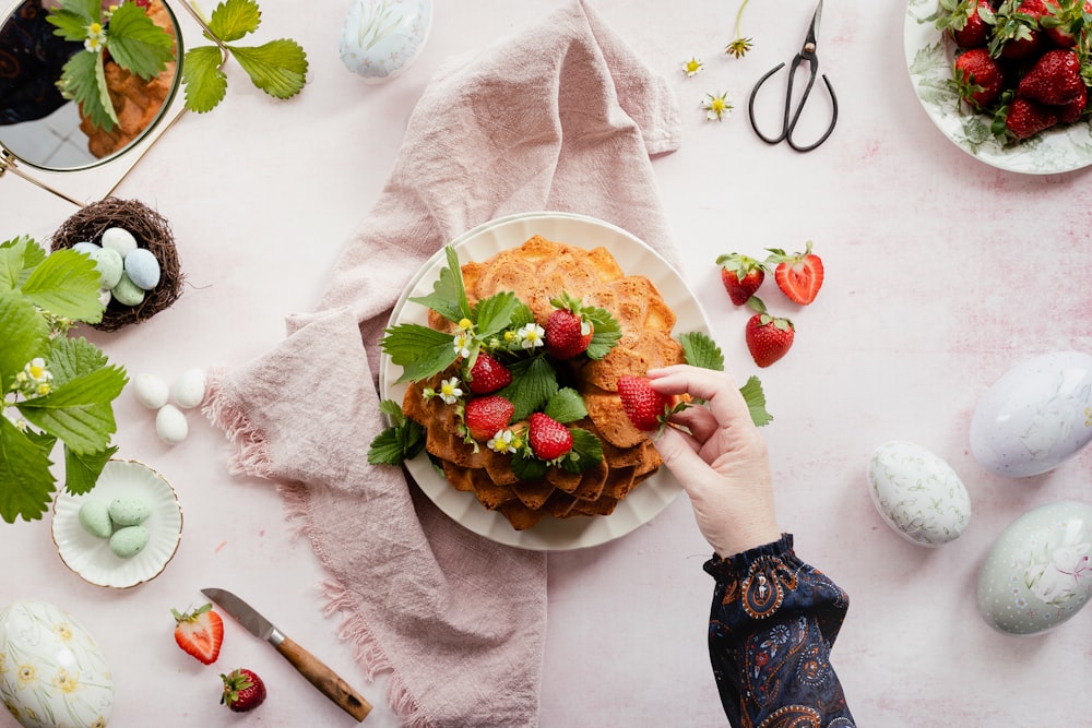 a person holding a plate of food with strawberries on it