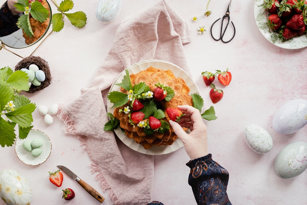 a person holding a plate of food with strawberries on it