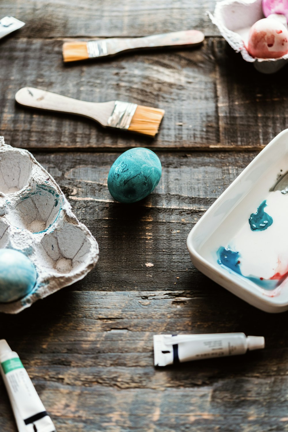 a wooden table topped with eggs and paint