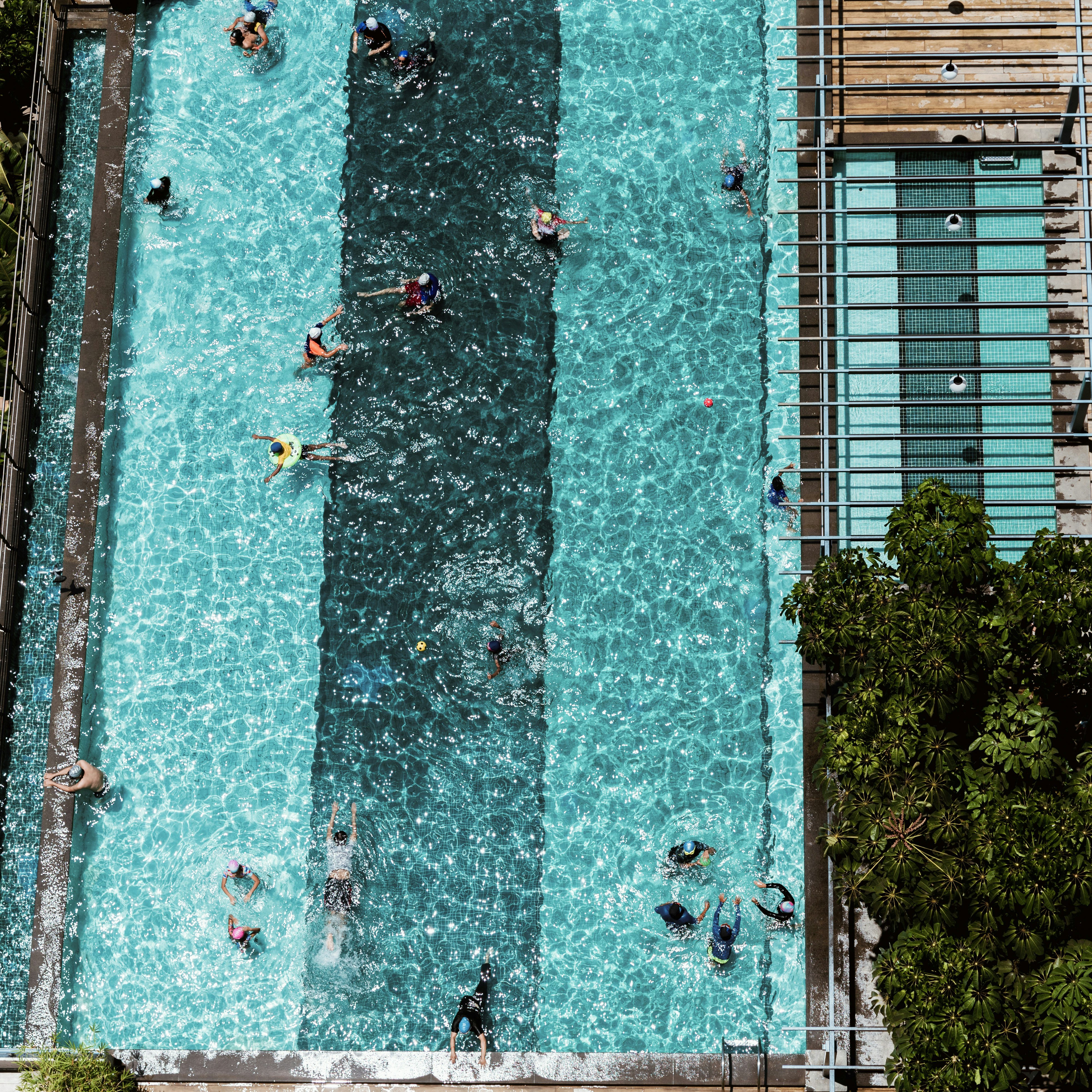 a group of people swimming in a pool next to a tall building