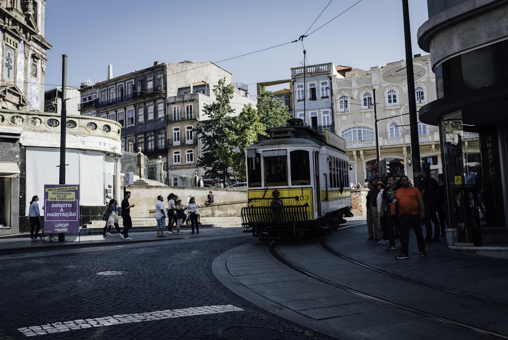 a yellow trolley car traveling down a street next to tall buildings