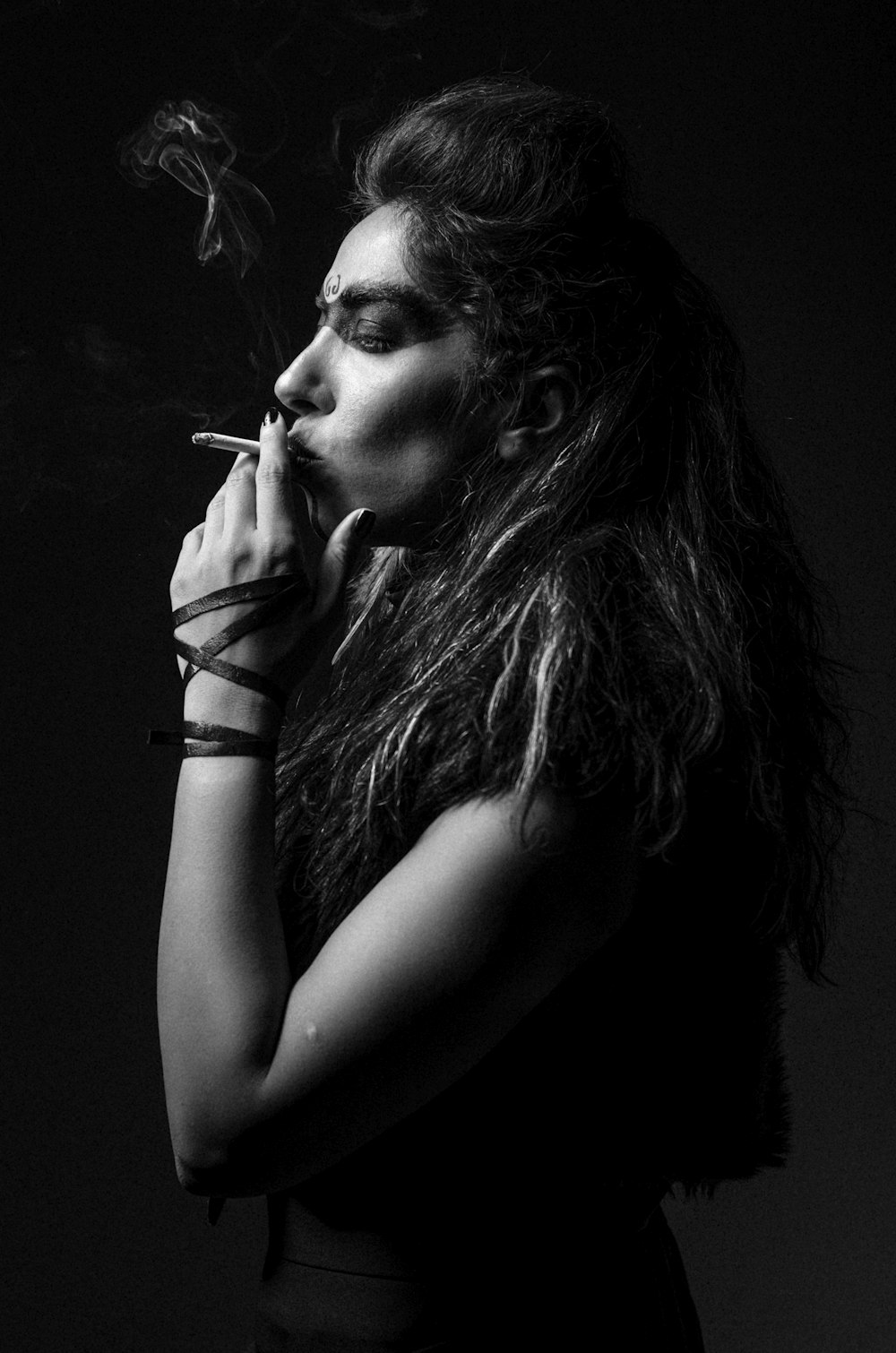 a woman smoking a cigarette in a black and white photo