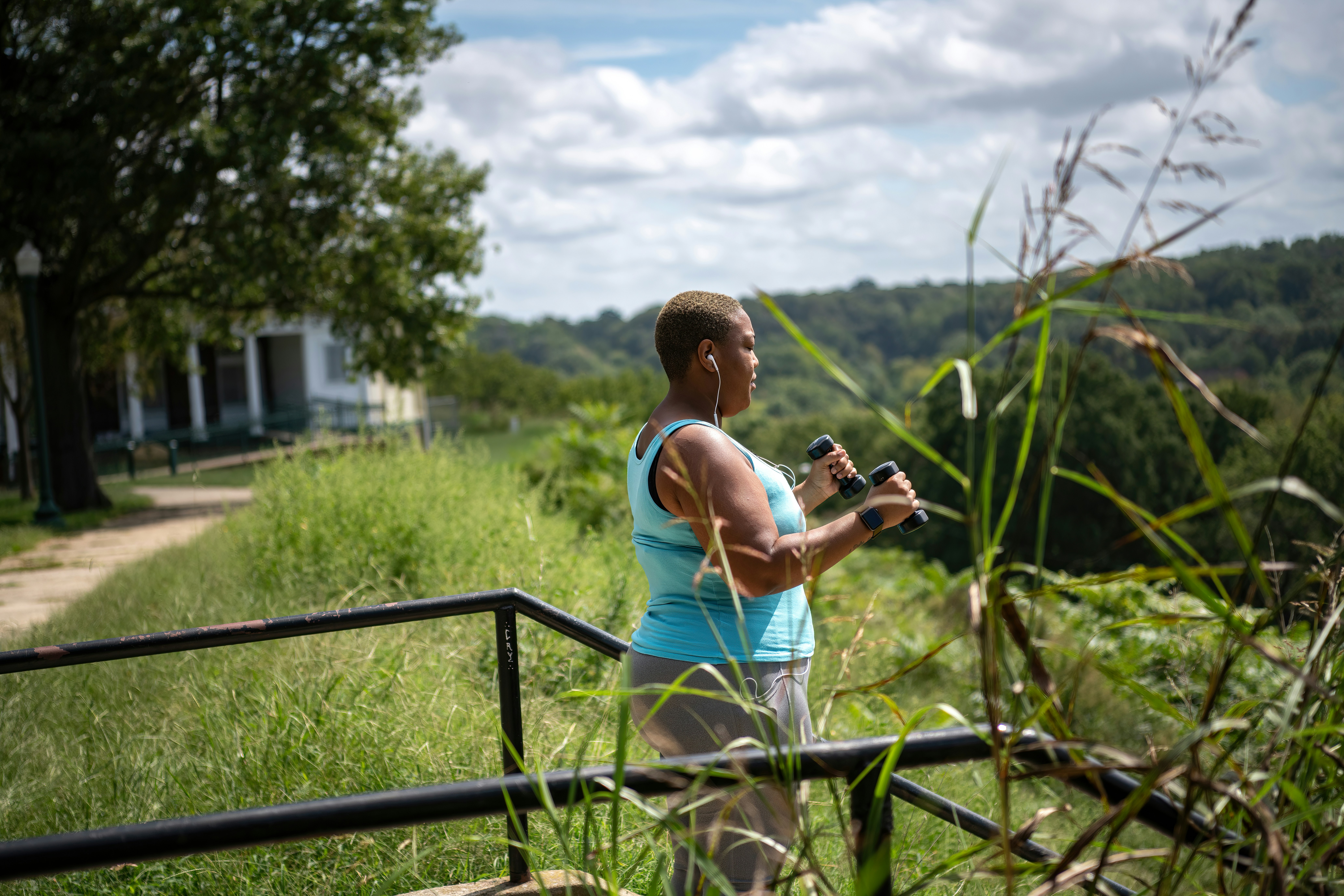 a woman holding a camera while standing next to a fence
