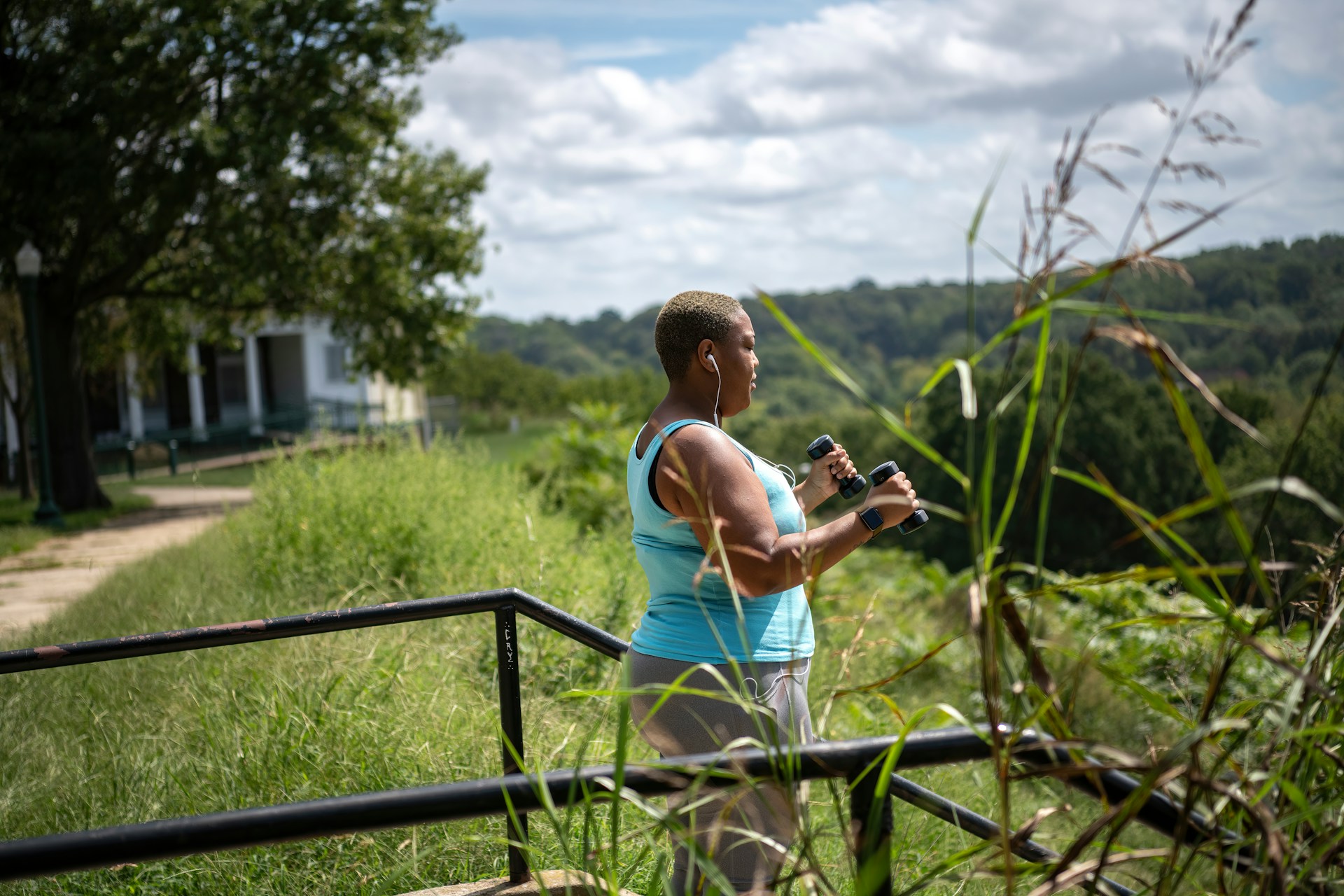 a woman holding a camera while standing next to a fence