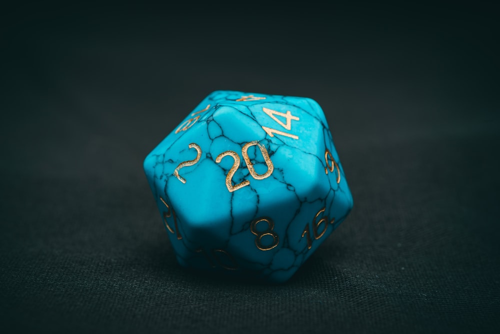 a blue dice with gold numbers on it