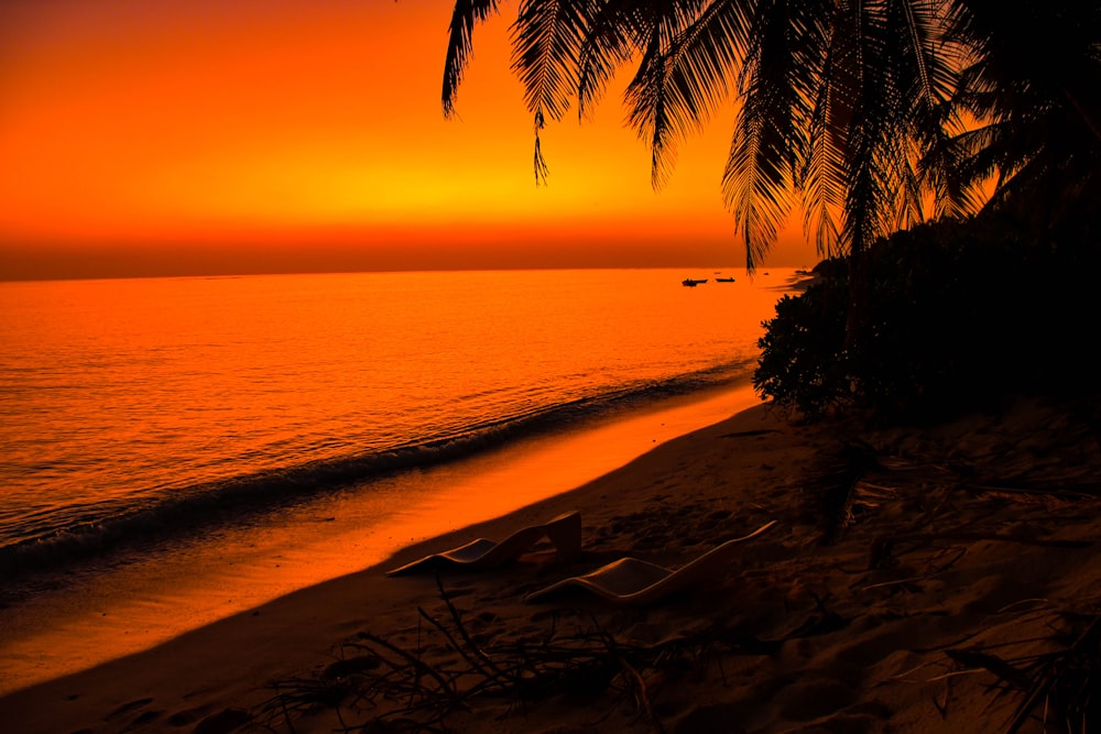 a sunset on a beach with a boat in the water