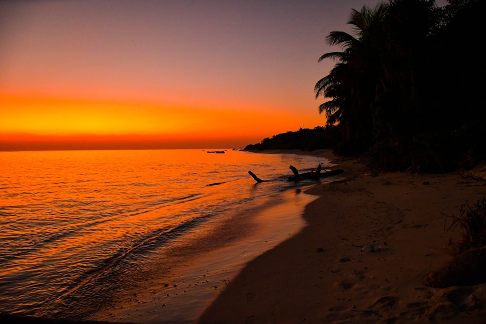 a sunset on a beach with a boat in the water