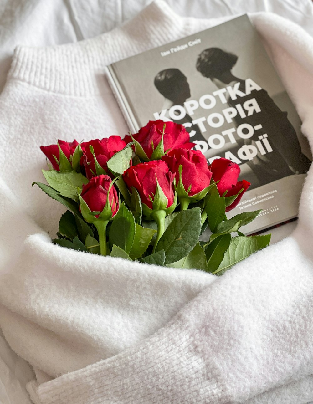a book and a bouquet of roses on a bed