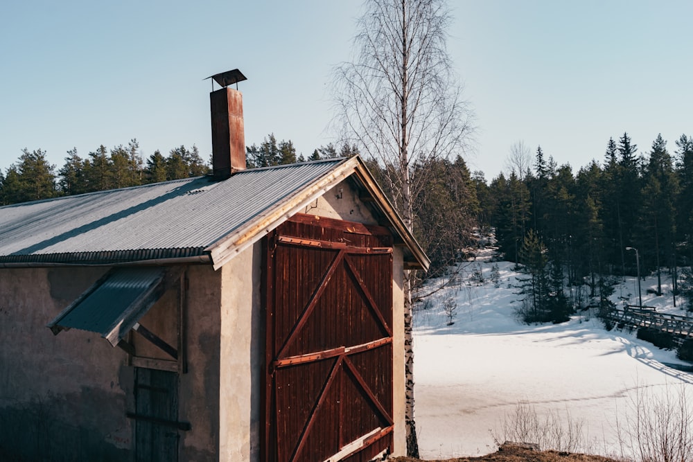 a small building with a metal roof next to a forest