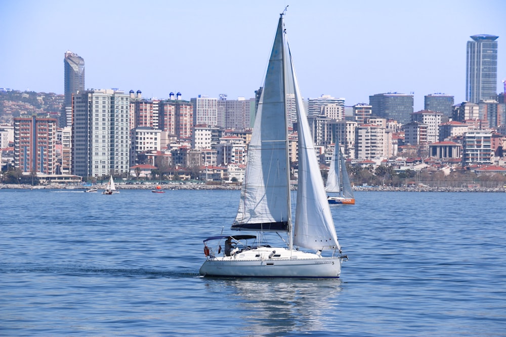 a sailboat in a body of water with a city in the background