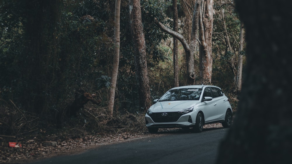 a white car driving down a forest road