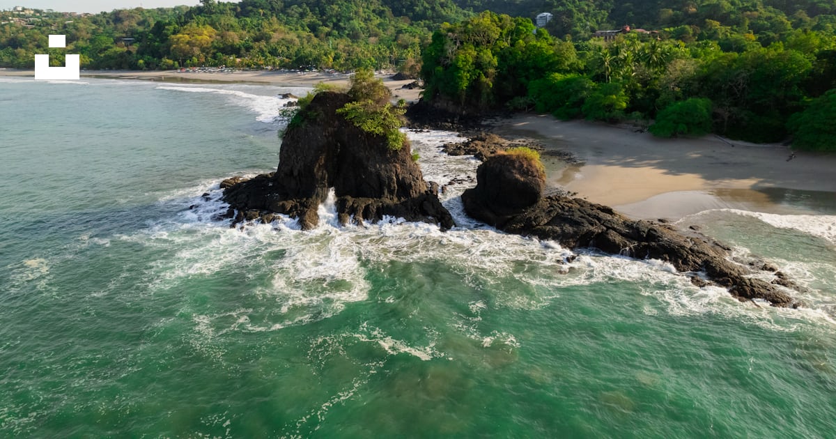 An aerial view of a beach with a rock formation in the middle of the ...