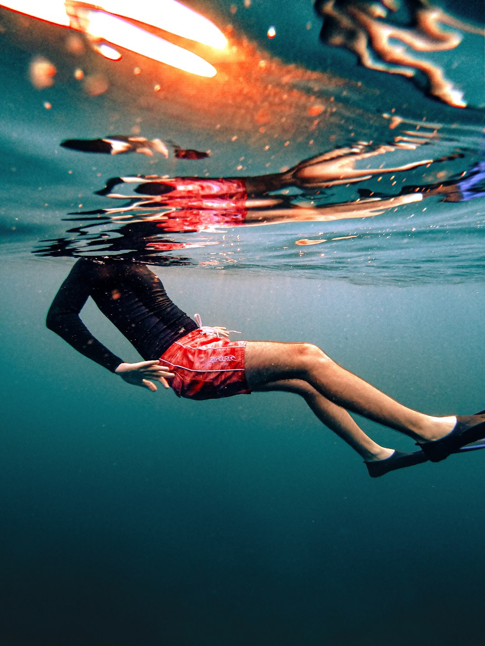 a woman is floating in the water with a surfboard