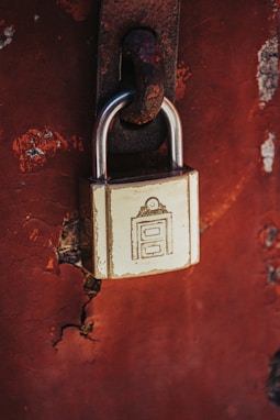 a padlock attached to a rusted red wall