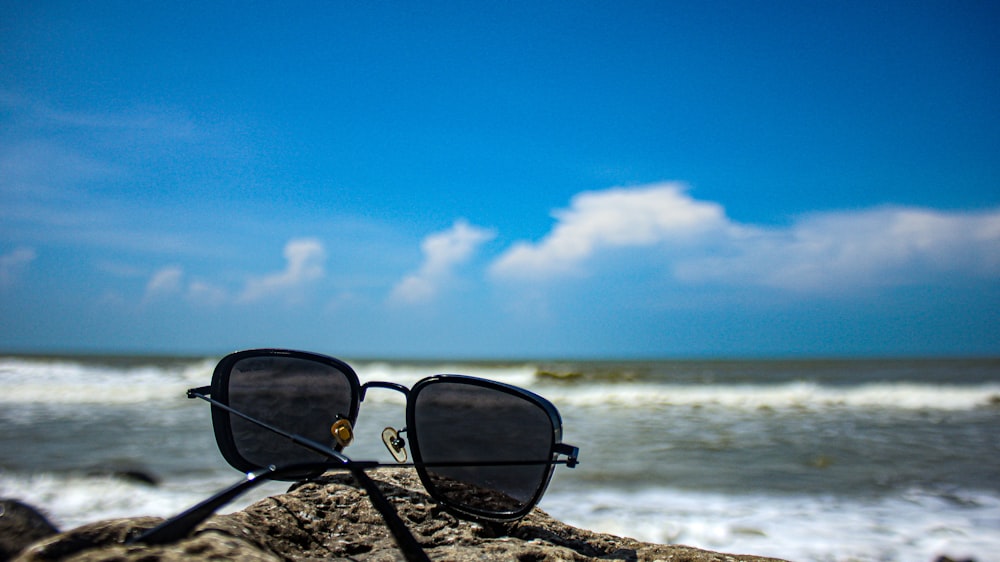 a pair of sunglasses sitting on top of a rock near the ocean